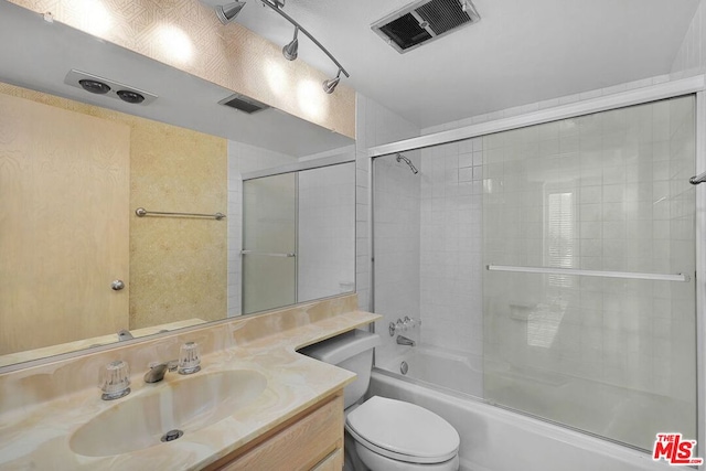 full bathroom featuring vanity, shower / bath combination with glass door, and toilet