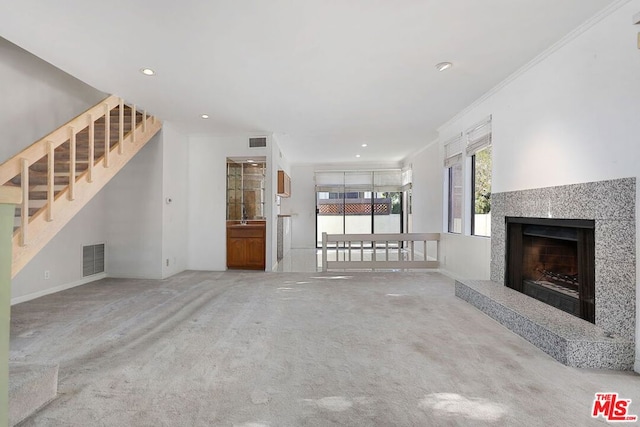 unfurnished living room with crown molding, light carpet, and a fireplace