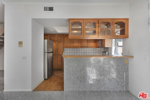 kitchen with appliances with stainless steel finishes, tasteful backsplash, parquet floors, kitchen peninsula, and crown molding