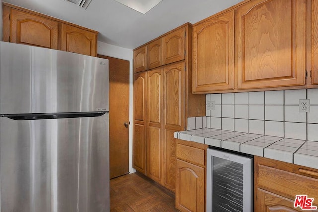 kitchen featuring stainless steel refrigerator, backsplash, wine cooler, dark parquet flooring, and tile countertops