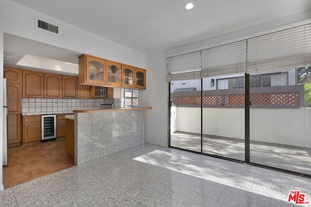 kitchen featuring crown molding, refrigerator, kitchen peninsula, beverage cooler, and backsplash