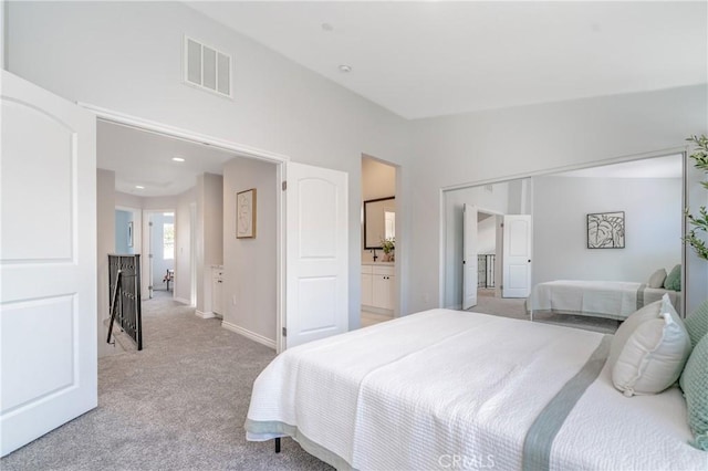 bedroom with baseboards, connected bathroom, visible vents, and light colored carpet