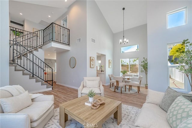 living room with stairs, visible vents, a chandelier, and light wood-style flooring