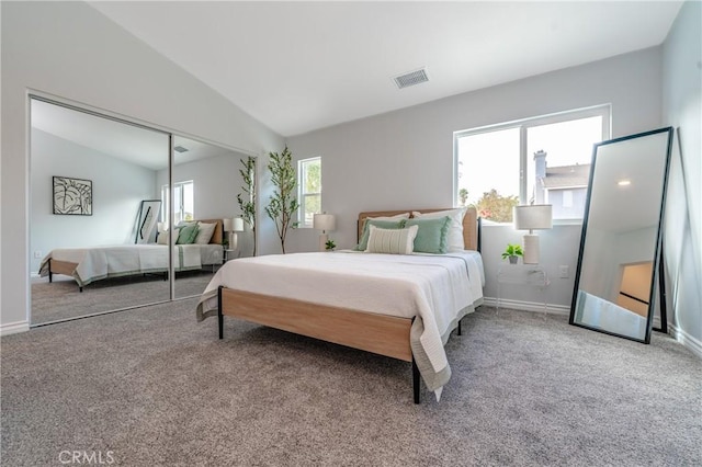 carpeted bedroom featuring a closet, visible vents, vaulted ceiling, and baseboards