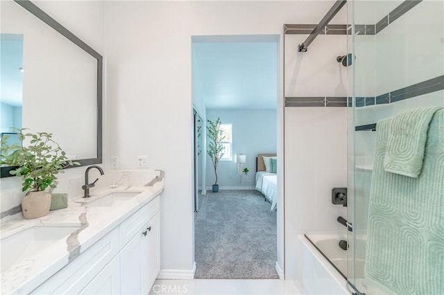full bath featuring a sink, double vanity, bath / shower combo with glass door, and connected bathroom