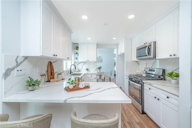 kitchen with stainless steel appliances, a peninsula, white cabinetry, and a kitchen breakfast bar