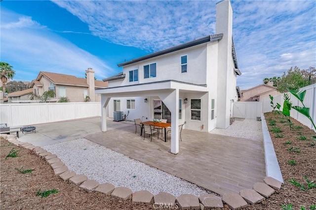 rear view of property with a patio, central AC unit, a fenced backyard, and stucco siding