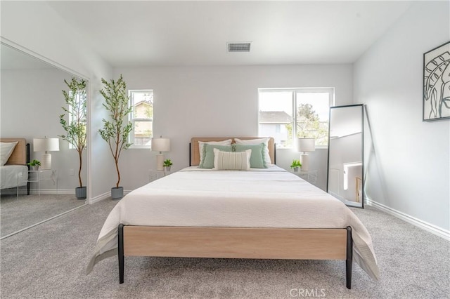 carpeted bedroom featuring baseboards, multiple windows, and visible vents