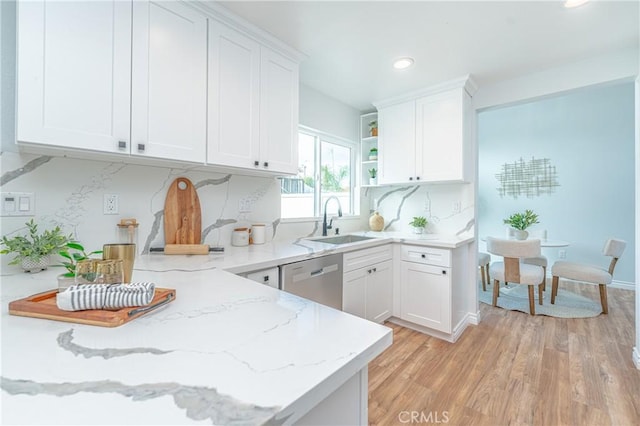 kitchen featuring open shelves, stainless steel dishwasher, white cabinets, a sink, and light stone countertops