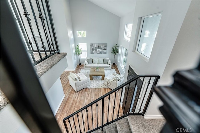 living area featuring high vaulted ceiling, plenty of natural light, and baseboards