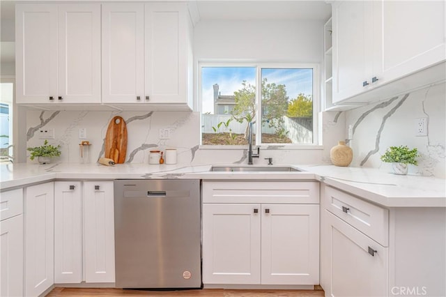 kitchen featuring stainless steel dishwasher, a sink, and white cabinets
