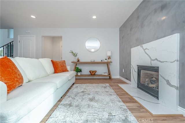 living room with stairs, recessed lighting, a fireplace, and wood finished floors