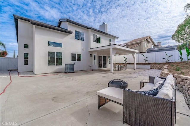 back of house with a patio, a fenced backyard, central AC, stucco siding, and an outdoor living space with a fire pit