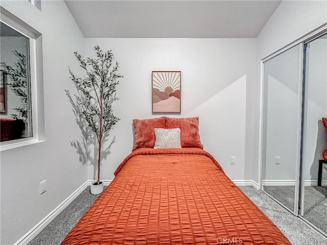 carpeted bedroom with a closet and baseboards