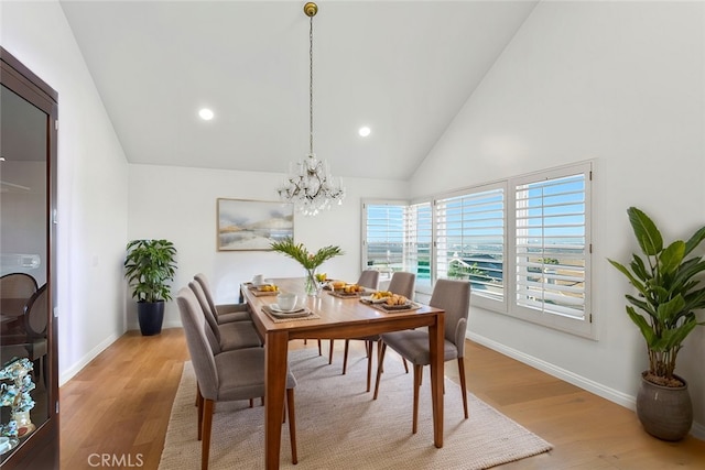 dining space with high vaulted ceiling, light hardwood / wood-style floors, and a notable chandelier