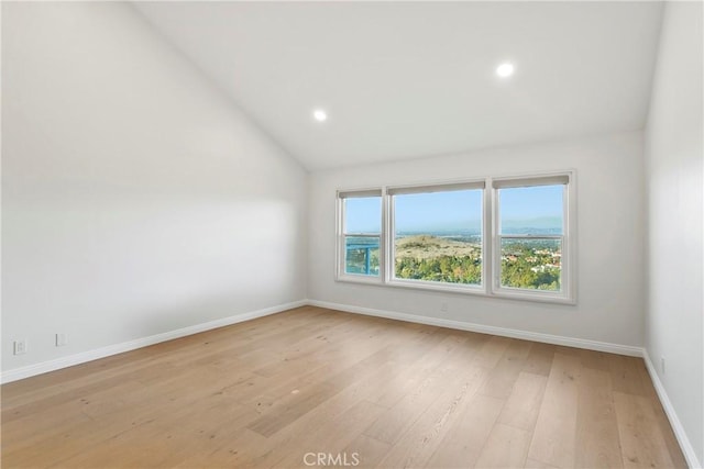 unfurnished room with vaulted ceiling and light wood-type flooring