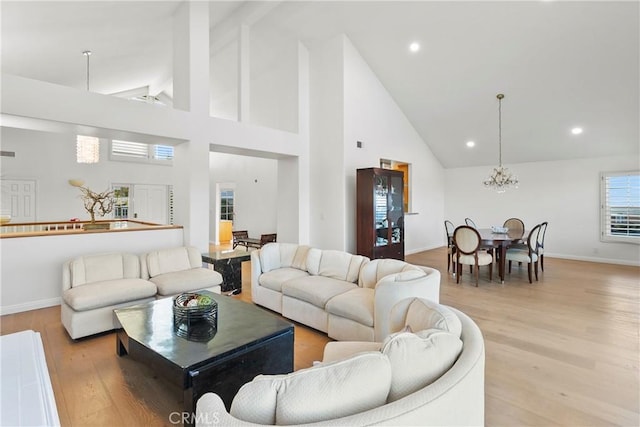 living room featuring high vaulted ceiling, a notable chandelier, and light wood-type flooring