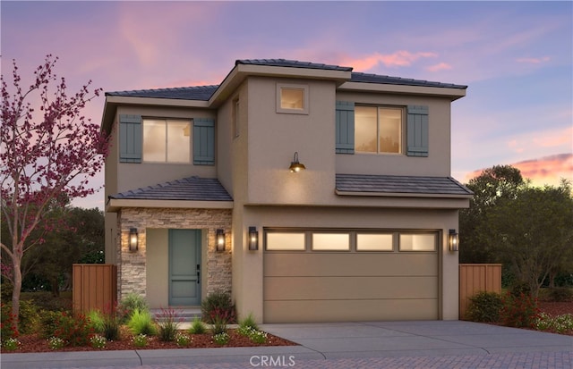 view of front of property featuring an attached garage, stone siding, concrete driveway, and stucco siding