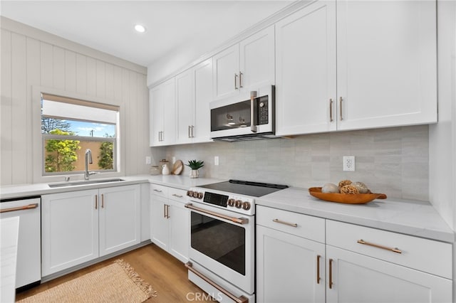 kitchen with white cabinetry, white appliances, tasteful backsplash, and a sink