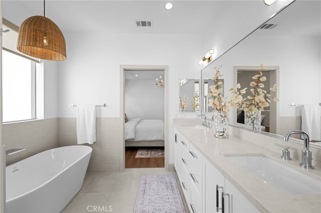 ensuite bathroom featuring a freestanding bath, connected bathroom, visible vents, and a sink