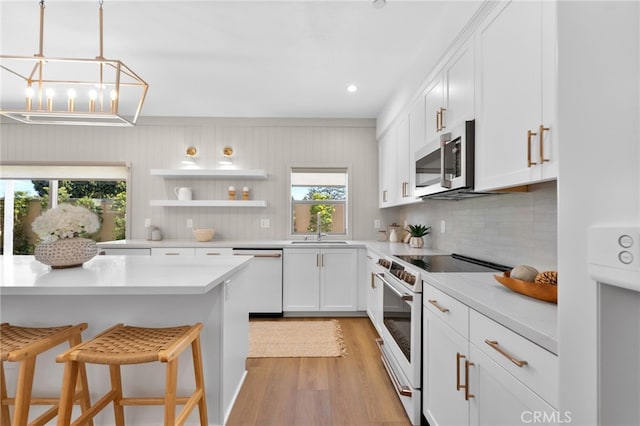 kitchen with tasteful backsplash, a breakfast bar area, light wood-style flooring, white appliances, and white cabinetry