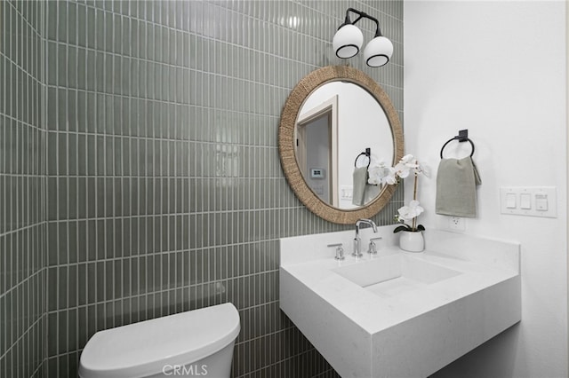 bathroom with tile walls, toilet, and a sink