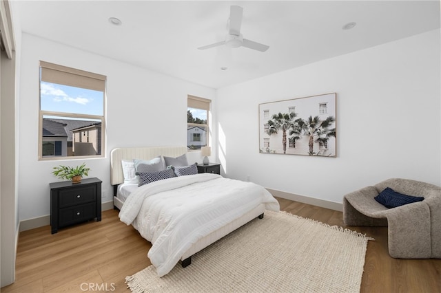 bedroom featuring light wood finished floors, a ceiling fan, and baseboards