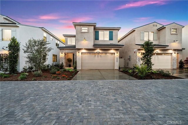 view of front of property featuring stone siding, stucco siding, an attached garage, and decorative driveway