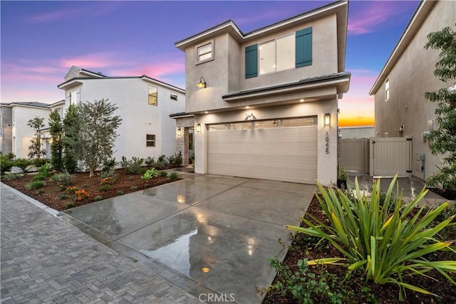 view of front of house featuring stucco siding, a gate, fence, concrete driveway, and an attached garage