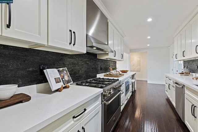 kitchen with stainless steel appliances, light stone countertops, white cabinets, and wall chimney exhaust hood