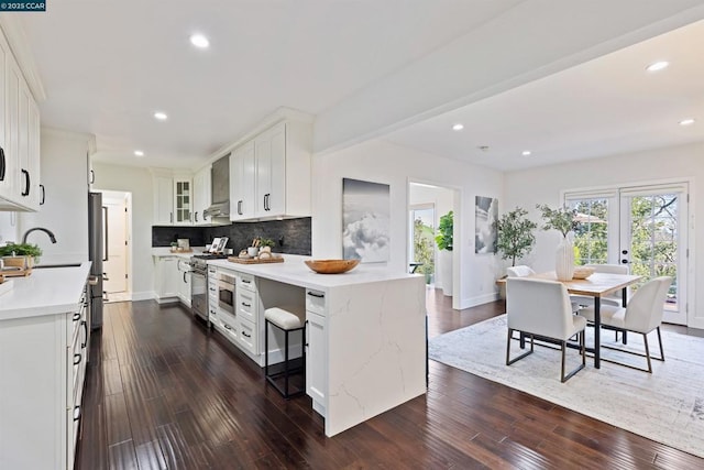 kitchen with backsplash, stainless steel appliances, dark hardwood / wood-style floors, and white cabinets