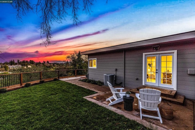 yard at dusk featuring a patio area, french doors, and central air condition unit