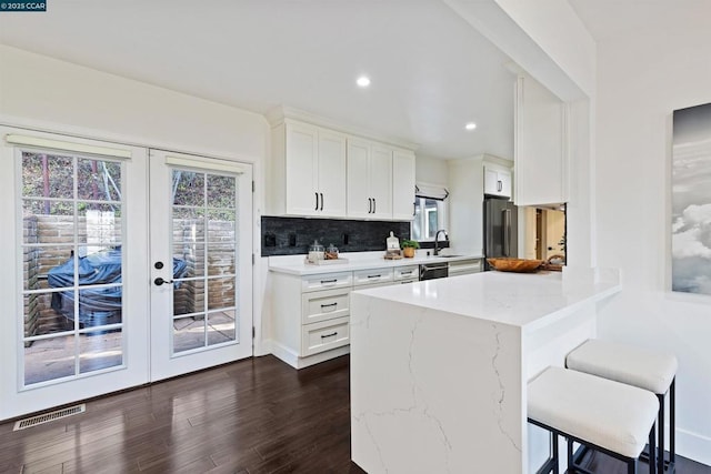 kitchen featuring sink, white cabinetry, stainless steel appliances, a kitchen bar, and french doors