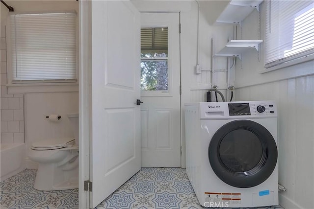 clothes washing area featuring washer / dryer, a healthy amount of sunlight, and light tile patterned floors