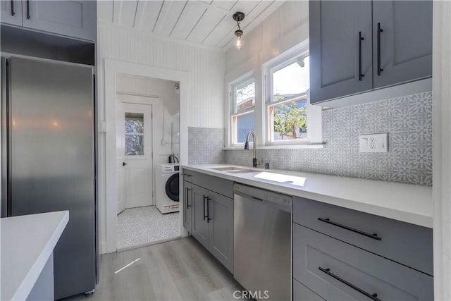 kitchen featuring gray cabinets, pendant lighting, washer / clothes dryer, sink, and stainless steel appliances