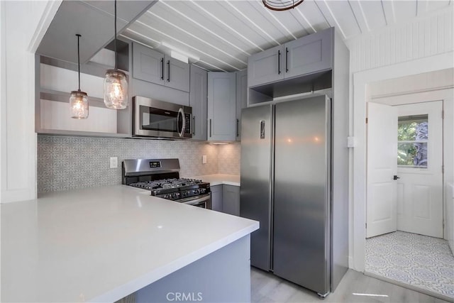 kitchen featuring appliances with stainless steel finishes, gray cabinetry, backsplash, hanging light fixtures, and kitchen peninsula