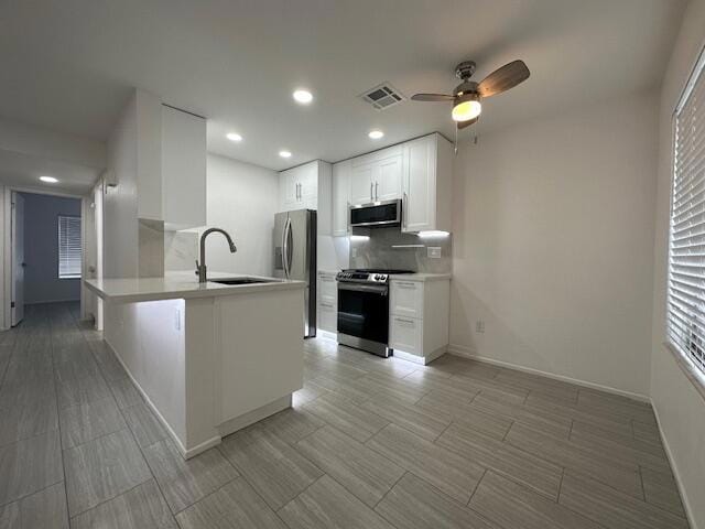 kitchen featuring stainless steel appliances, white cabinetry, sink, and kitchen peninsula