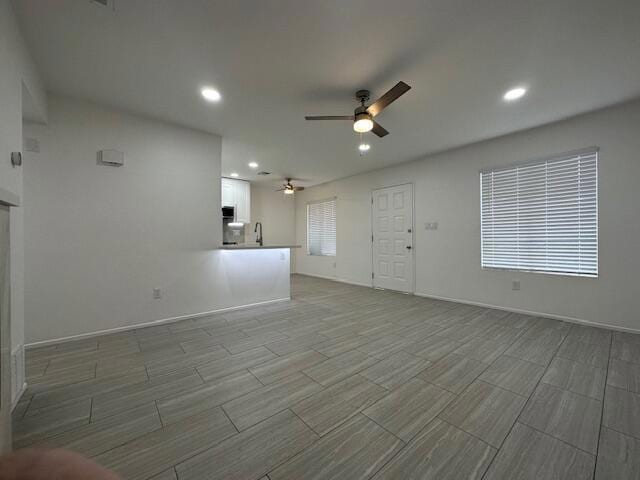 unfurnished living room with sink and ceiling fan