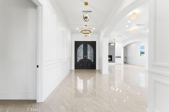 entryway with crown molding, a large fireplace, and french doors