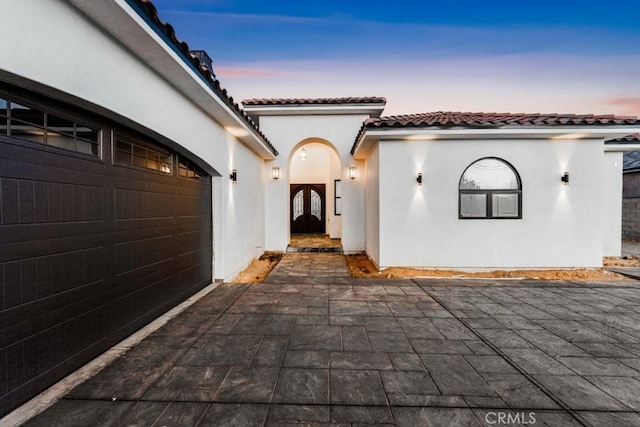 exterior entry at dusk featuring a garage