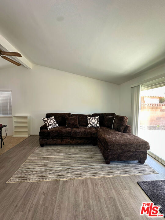 living room featuring hardwood / wood-style flooring, vaulted ceiling with beams, and ceiling fan