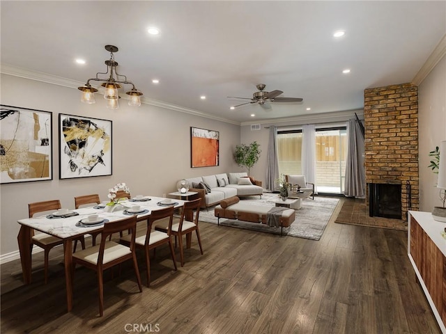 dining area featuring crown molding, dark wood-type flooring, ceiling fan, and a fireplace