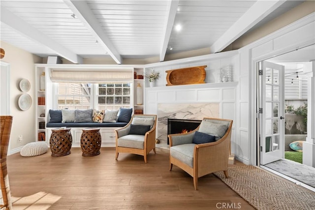 living area featuring beam ceiling, hardwood / wood-style flooring, and a fireplace