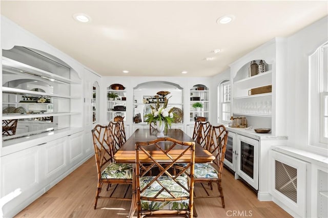 dining room with wine cooler, light wood-type flooring, and built in shelves