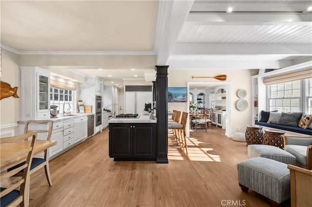 kitchen with white cabinetry, sink, beam ceiling, and light hardwood / wood-style flooring