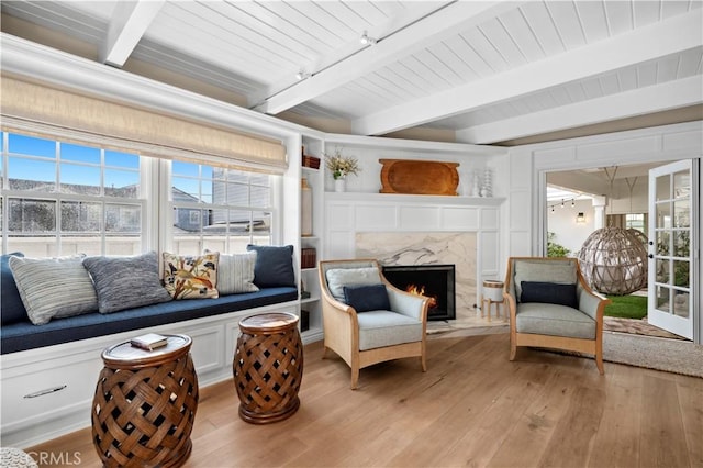 sunroom / solarium with a premium fireplace, rail lighting, wood ceiling, and beam ceiling