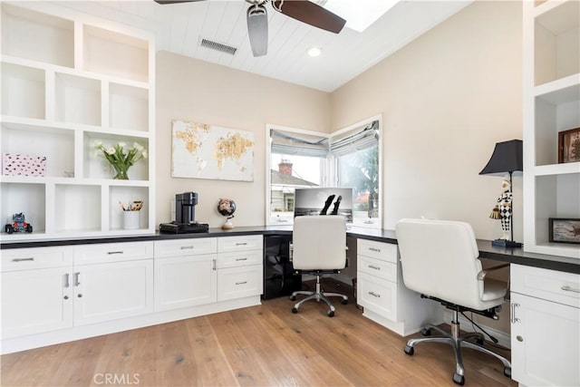 home office featuring ceiling fan, built in desk, light wood-type flooring, and built in shelves