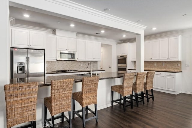 kitchen featuring a kitchen bar, sink, white cabinetry, a large island with sink, and stainless steel appliances