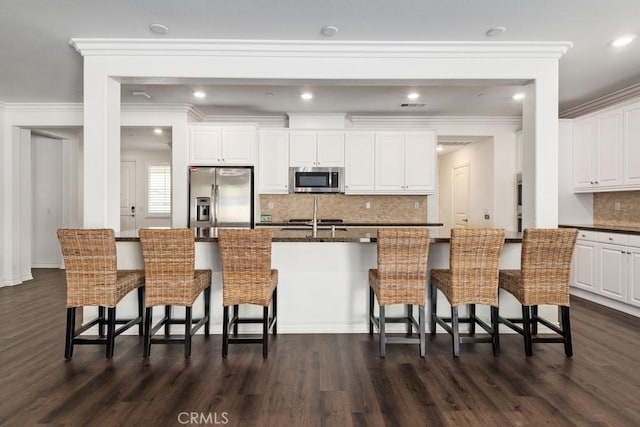 kitchen featuring white cabinetry, stainless steel appliances, a breakfast bar area, and a center island with sink