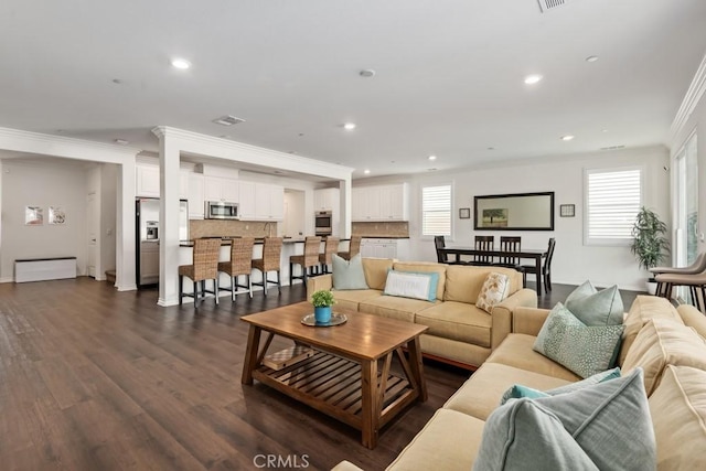 living room with crown molding, plenty of natural light, and dark hardwood / wood-style floors